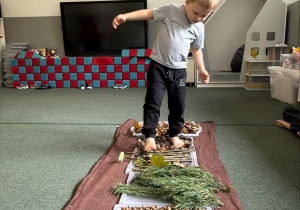 dzieci chodzą boso po jesiennej ścieżce sensorycznej z materiałów naturalnych
