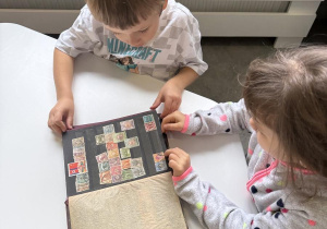 dzieci oglądają klaser ze znaczkami pocztowymi