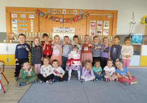 Zdjęcie grupowe w sali z dziewczynką obchodzącą urodziny