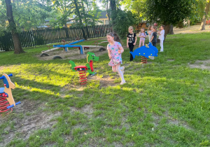 Dziewczynka pokonuje slalomem tor z bujaków w ogrodzie przedszkolnym