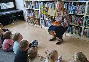 Dzieci słuchają książki czytanej przez Panią Bibliotekarkę