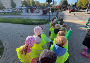 Dzieci podczas spaceru na skrzyżowanie czekają na zielone światło, by móc przejść przez jezdnię