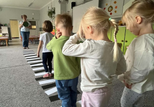Dzieci w sali przedszkolnej ćwiczą przechodzenie przez jezdnię na zielonym świetle