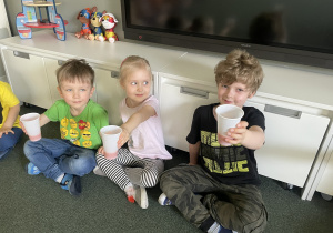 dzieci trzymają kubki z sokiem marchwiowym