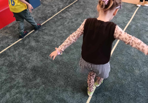 Dzieci idą tyłem po liniach wyznaczonych na dywanie