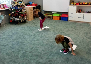 Dzieci przemieszczają się na dywanie po kartkach A4
