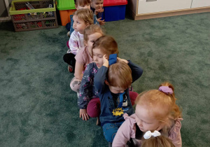 Dzieci w siadzie skrzyżnym podają sobie woreczek nad głowami