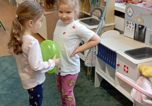 Dziewczynki próbują utrzymać balon między swoimi brzuchami