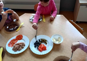 Dziewczynka częstuje się oliwkami podczas śniadania w stylu hiszpańskim