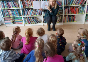 Dzieci słuchają czytanej przez panią bibliotekarkę książki