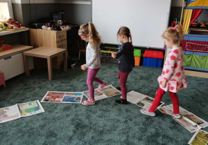 Dziewczynki idą nadeptując gazety jedną nogą