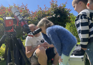 dzieci kolejno obserwują Słońce przez teleskop słoneczny