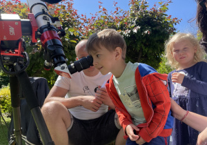 dzieci kolejno obserwują Słońce przez teleskop słoneczny