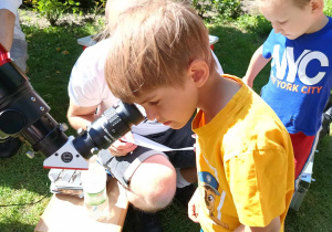 Chłopiec obserwuje słońce przez teleskop