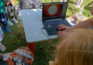 Dzieci obserwują słońce widoczne przez kamerę astronomiczną