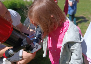 Dziewczynka obserwuje słońce przez teleskop
