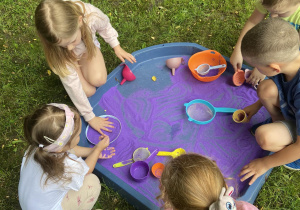 Dzieci podczas zabawy fioletowym piaskiem kinetycznym