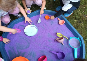 Dzieci podczas zabawy fioletowym piaskiem kinetycznym