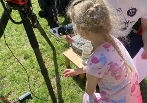 Dziewczynka oglądająca słońce przez teleskop