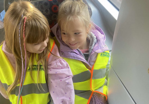 Dziewczynki podczas podróży tramwajem w odblaskowych kamizelkach.