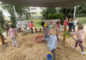 Dzieci podczas zabaw sensorycznych w ogrodzie przedszkolnym.