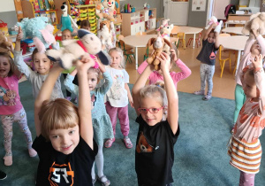Dzieci podnoszą do góry swoje pluszowe pieski