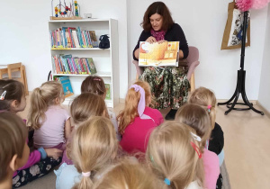 Dzieci oglądają ilustrację w książce "10 kotów" trzymanej przez jej autorkę
