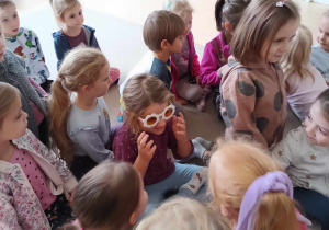 Dzieci przyglądają się dziewczynce, która przymierzyła żółte okulary