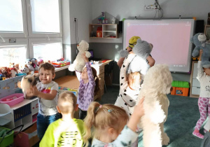 Dzieci tańczą z pluszowymi misiami trzymając je nad głowami