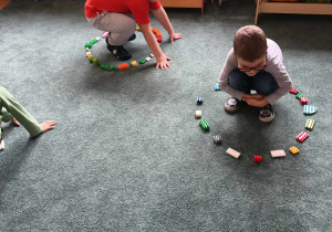 Chłopcy kucają na dywanie w kołach ułożonych z klocków LEGO
