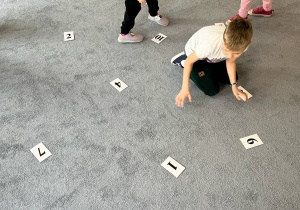 Dzieci na dywanie w poszukiwaniu liczny na odpowiedniej kartce