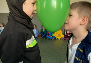 Chłopcy podczas zabawy karnawałowej, tańczący z balonami pomiędzy głowami