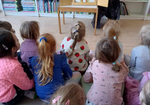 Dzieci słuchają bajki Teatrzyku Kamishibai czytanej przez panią bibliotekarkę