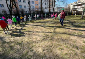 Dzieci z nauczycielką podczas zabawy ruchowej na powitanie wiosny