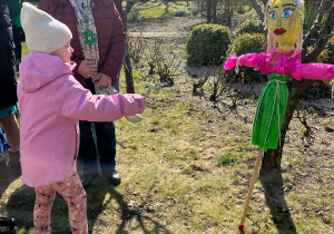 Dziewczynka polewa Marzannę wodą z chochli