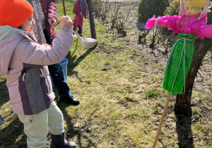 Dziewczynka polewa Marzannę wodą z chochli