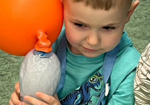 Chłopiec trzyma butelkę z suchym lodem, dzięki któremu napompowuje się umieszczony na butelce balon