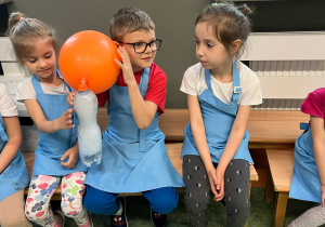 Chłopiec trzyma butelkę z suchym lodem, dzięki któremu napompowuje się umieszczony na butelce balon