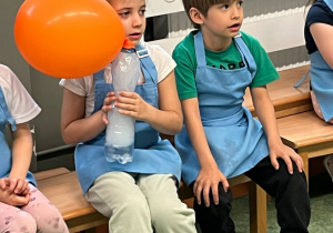 Dziewczynka trzyma butelkę z suchym lodem, dzięki któremu napompowuje się umieszczony na butelce balon