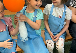 Dziewczynka trzyma butelkę z suchym lodem, dzięki któremu napompowuje się umieszczony na butelce balon