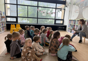 dzieci w bibliotece słuchają edukatorki