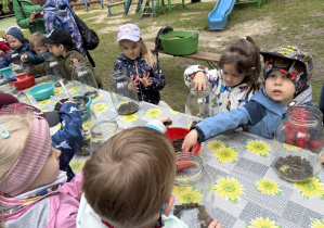 dzieci podczas warsztatów botanicznych wykonują las w słoiku