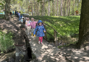 dzieci przechodzą przez drewniany mostek nad rzeczką