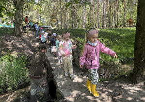 dzieci przechodzą przez drewniany mostek nad rzeczką