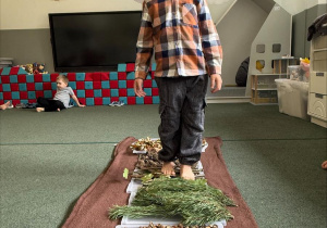 dzieci chodzą boso po jesiennej ścieżce sensorycznej z materiałów naturalnych