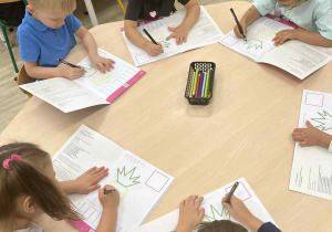 Dzieci podczas pracy w książce ćwiczeniowej przy stolikach