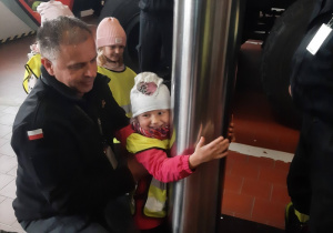 Dziewczynka zjeżdzająca na rurze strażackiej