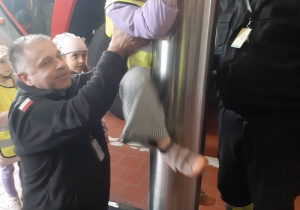 Dziewczynka zjeżdzająca na rurze strażackiej