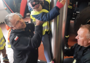 Dziewczynka zjeżdzająca na rurze strażackiej