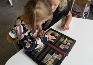 dzieci oglądają klaser ze znaczkami pocztowymi